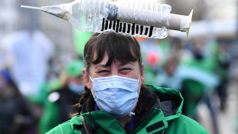 Una trabajadora de la salud lleva un elemento simbólico en forma de jeringa en la cabeza mientras participa en una manifestación sindical contra la vacunación obligatoria, en Bruselas el 7 de diciembre de 2021.