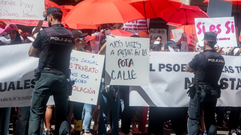 Varias personas con pancartas y paraguas rojos, frente a la policía, protestan durante una concentración, en la sede del PSOE en calle Ferraz, a 2 de junio de 2022, en Madrid (España).