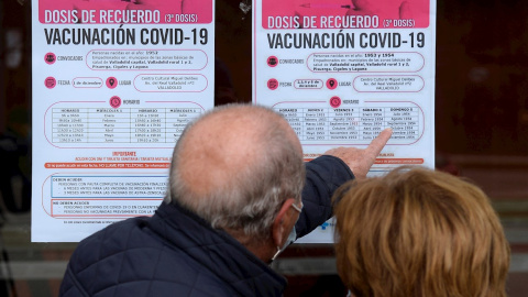 Dos personas observan un cartel con las pautas para recibir la tercera dosis de Pfizer en Valladolid este miércoles en el que el Ministerio de Sanidad ha recomendado limitar el número de participantes en los "eventos públicos y sociales", especialm