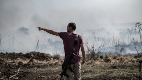 Un hombre armado se encuentra cerca de un incendio causado por ataques con misiles y drones en el Líbano. Imagen de archivo.