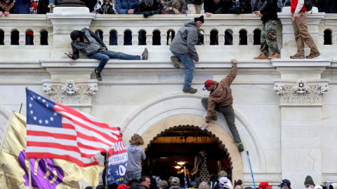 Partidarios del expresidente de Estados Unidos, Donald Trump, se pelean con miembros de las fuerzas del orden en una puerta que rompieron mientras irrumpen en el edificio del Capitolio de Estados Unidos, en Washington, Estados Unidos, el 6 de enero de 202