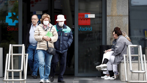 Dos personas mayores con mascarillas caminan junto a la entrada del hospital La Paz de Madrid. - EFE