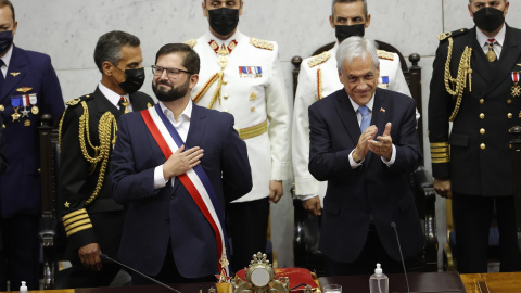 El presidente de Chile Gabriel Boric saluda a los asistentes al Congreso Nacional luego de recibir la banda presidencial, mientras el expresidente Sebastián Piñera (der.) aplaude este 11 de marzo de 2022.