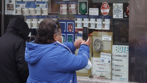 Varias personas en una administración de lotería de Navidad de la Puerta del Sol cuando quedan menos de tres semanas para el Sorteo Extraordinario de la Lotería de Navidad, a 7 de diciembre de 2021, en Madrid (España).