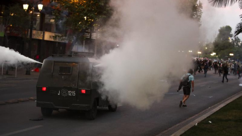 Carabineros de Chile rocía a los manifestantes con gas lacrimógeno este viernes en el marco de las protestas contra el alza del billete de Metro, en el centro de Santiago (Chile). Las protestas por el alza del precio del tiquete del Metro de Santiago se