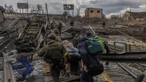 Militares ucranianos llevan a una anciana en silla de ruedas en una zona bombardeada en la ciudad de Irpin, en la región de Kiev, este 7 de marzo de 2022.