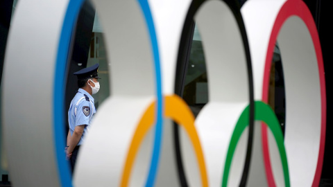 Un guardia de seguridad detrás del monumento de los anillos olímpicos en las inmediaciones del estadio olímpico de Tokio.