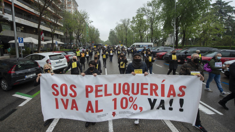 Un grupo de personas sostiene una pancarta donde se puede leer "SOS Peluquerías IVA al 10% ya!" en una concentración del sector de la imagen, a 26 de abril de 2021