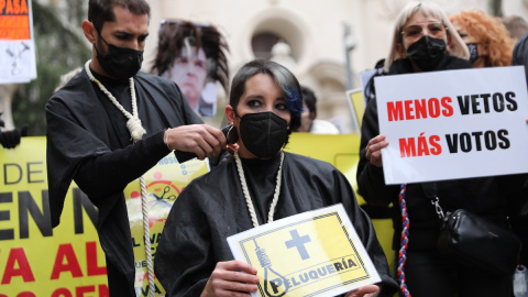 Un hombre rapa a una mujer durante una protesta de profesionales de peluquería y estética, frente al Senado, a 9 de diciembre de 2021, en Madrid.