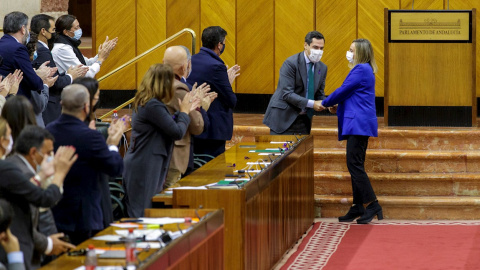 25/11/2021.- El presidente de la Junta, Juanma Moreno (2d), felicita a la consejera de Fomento, Marifrán Carazo (d), en el Pleno del Parlamento de Andalucía en Sevilla que ha aprobado este jueves 25 de noviembre la Ley del Suelo.