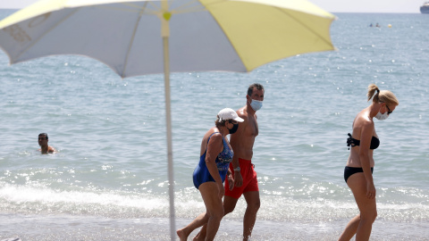 Bañistas con mascarilla pasean por la orilla de la playa de La Malagueta