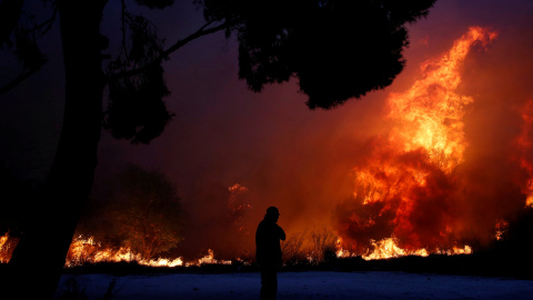 Un hombre observa las llamas del incendio en la ciudad de Rafina. REUTERS/Costas Baltas