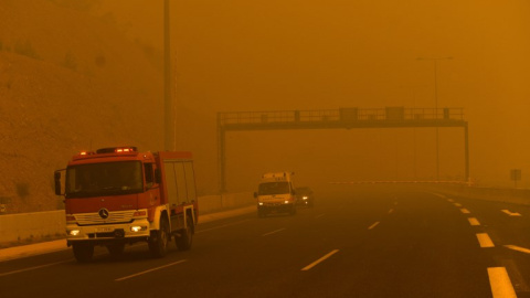 Un coche de bomberos se observa entre el humo del incendio en Kineta, cerca de Atenas - AFP