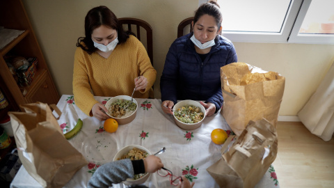 Dos mujeres y un niño durante la comida en su casa del barrio madrileño de Carabanchel prueban el menú de la ONG del chef José Andrés.