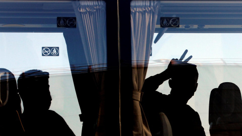 Una persona saluda desde el autobús tras desembarcar del ferry en el que viajaban 118 estudiantes que habían sido confinados en un hotel de Mallorca tras el macrobrote detectado en la isla.