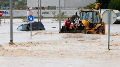 Dos ocupantes de un vehículo son rescatados con una pala mecánica, mientras la carretera permanece inundada por el efecto de las riadas, este viernes, en la ciudad alicantina de Orihuela, que se encuentra incomunicada, a causa del desbordamiento del rí