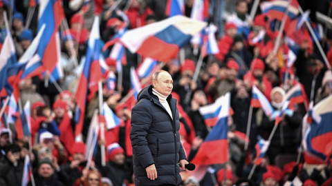 La multitud ondea banderas rusas mientras el presidente ruso Vladimir Putin camina para pronunciar un discurso durante un concierto celebrado para conmemorar el octavo aniversario de la anexión de Crimea por parte de Rusia en el estadio Luzhniki.