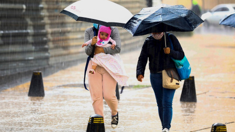 Personas se resguardan de la lluvia este miércoles.