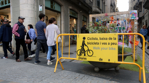 Un cartell al carrer Nou de Girona demanant als ciclistes que vagin a peu