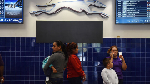 Unas madres y sus hijos esperan el autobús tras ser liberados se un centro de San Antonio (Texas). (REUTERS)