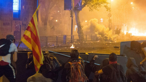 Jóvenes encapuchados se parapetan tras barricadas en el centro de la calle tras prender fuego a contenedores en el centro de Barcelona. GUILLEM SANS