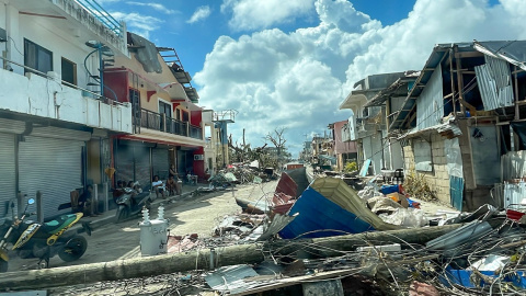 Un poste de luz y casas destruidas en Filipinas tras el paso del tifón Rai.