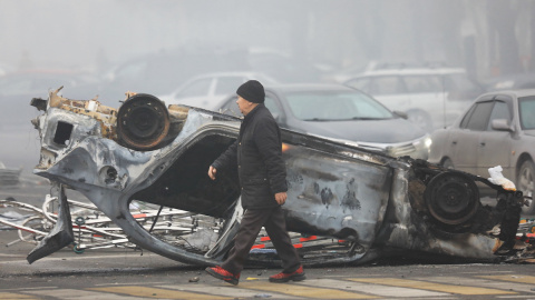 Un hombre pasa junto a un automóvil que se quemó durante las protestas provocadas por el aumento del precio del combustible en Almaty, Kazajstán, el 6 de enero de 2022.