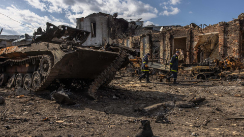 Rescatistas ucranianos pasan junto a un tanque ruso destruido junto a una estación de tren en la ciudad recuperada por el ejército ucraniano de Trostyanets este 30 de marzo de 2022.