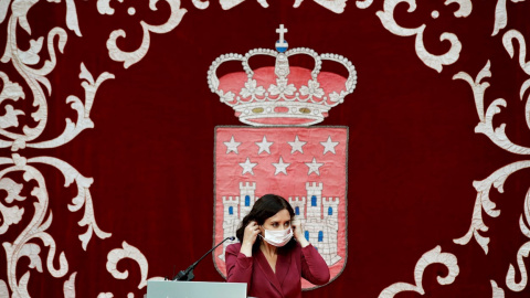 La presidenta madrileña, Isabel Díaz Ayuso, se coloca la mascarilla mientras preside la ceremonia de toma de posesión de los nuevos consejeros de la Comunidad de Madrid, este lunes, en la Real Casa de Correos.