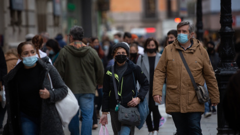 Viandantes caminan con bolsas por una vía de Barcelona, a 27 de diciembre de 2021.