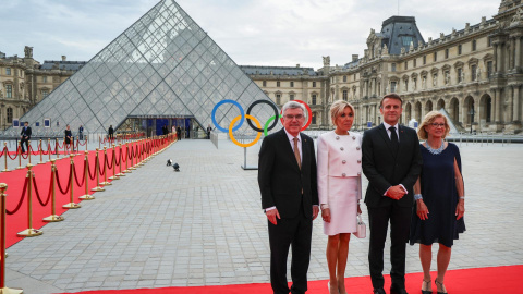 El presidente del Comité Olímpico Internacional (COI), Thomas Bach (i), y su esposa Claudia Bach (d), posan con el presidente francés, Emmanuel Macron, y su esposa, Brigitte Macron, a su llegada a la pirámide del Louvre.