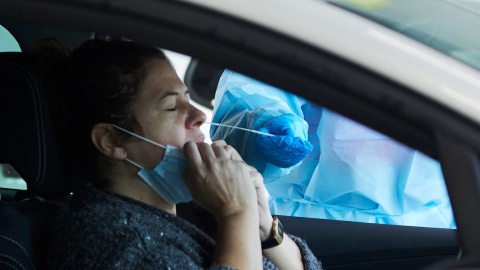 Una sanitaria le realiza la prueba PCR a una mujer en su coche durante la realización de PCR en el autocovid instalado en el Hospital Militar, a 28 de diciembre de 2021 en Sevilla.