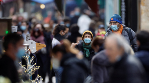 Personas, con máscaras protectoras, caminan por la calle Mouffetard, en medio de la propagación de la pandemia en París, Francia, 30 de diciembre de 2021.