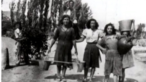 Las mujeres de Lanaja cogen agua de los barreños para hacerlo llegar a casa