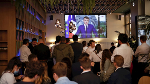 Clientes de un bar en París escuchan al presidente francés, Emmanuel Macron, durante su intervención ante la televisión.