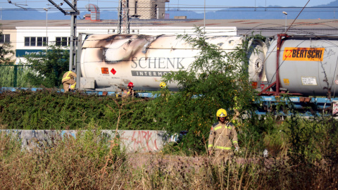 Els Bombers al costat del vagó del tren de mercaderies que s'ha incendiat a Girona