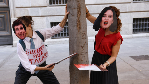 Dos personas con caretas de Almeida y Ayuso fingen talar un árbol durante una manifestación contra la tala de árboles por la ampliación de la L11 de Metro, en la Puerta del Sol, a 8 de octubre de 2023, en Madrid (España).