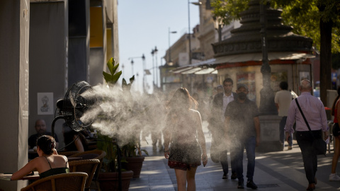 Varias personas caminan al lado de un difusor de vapor de agua de un restaurante en Madrid, en una imagen del 2 de julio de 2021.