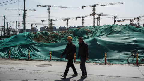 Dos trabajadores migrantes caminan cerca de una obra en Pekín. EFE/EPA/WU HONG