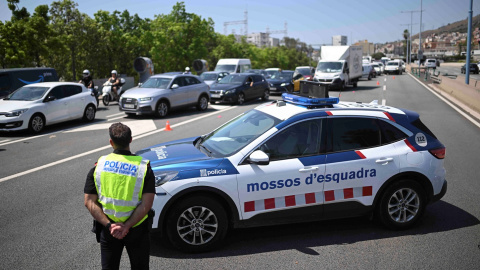 Un agente de los Mossos de Escuadra junto a un vehículo policial, en uno de los controles de carreteras establecidos en Barelona para localizar al expresidente Carles Puigdemont, tras su desparición después de una breve intervención en su reaparición