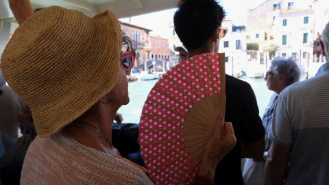 Foto de archivo de una persona con un abanico dentro de un autobús, en Venecia.