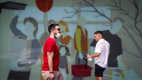 Dos hombres caminan con la mascarilla quitada este sábado en San Sebastián.