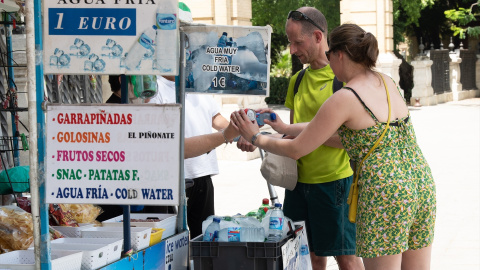 19/07/2024 Unos turistas compran agua en un puesto callejero de la ciudad de Sevilla. Foto de archivo.