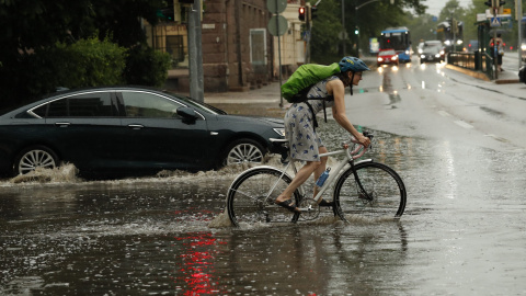 Mujer en bicicleta bajo la lluvia. Foto de archivo.