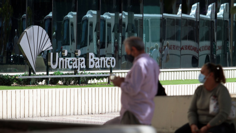 Dos personas en las inmediaciones de la sede de Unicaja Banco en Málaga. E.P./Álex Zea