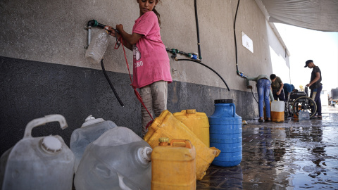 Foto de archivo de una niña palestina llenando garrafas de agua.