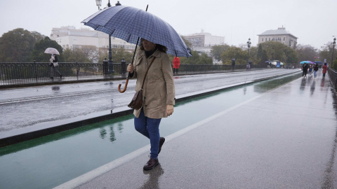 1/4/22-Una señora cruza el puente de Isabel II durante la lluvia caída en la capital andaluza, a 11 de marzo de 2022 en Sevilla.