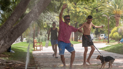 Varias personas se refrescan en una boca de riego en un jardín de Murcia.