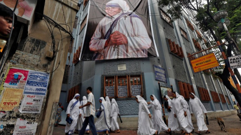 Monjas pertenecientes a las Misioneras de la Caridad pasan junto a una gran pancarta de la Madre Teresa - REUTERS