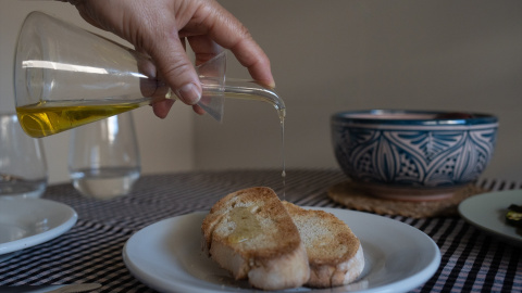 Una persona echa aceite de una aceitera a una tostada en Barcelona, Catalunya (España).